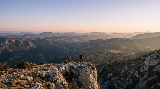 Randonneur solitaire contemplant un vaste plateau minéral des Préalpes de Haute-Provence au lever du jour, loin de toute foule